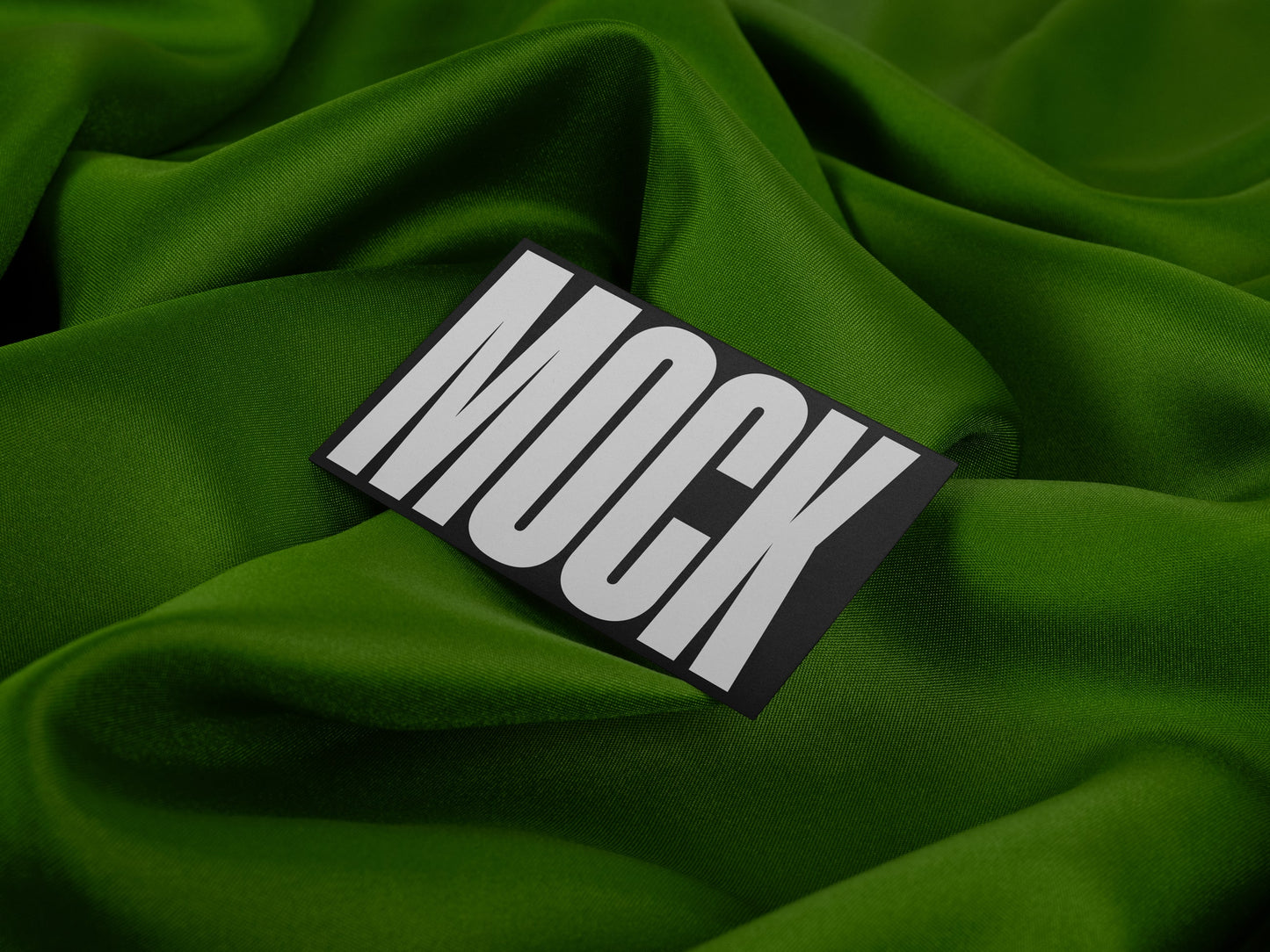 High-quality branding mockup featuring stationery print items, showing a business card on a green background made of cloth fabric. Created by Sylvan Hillebrand.