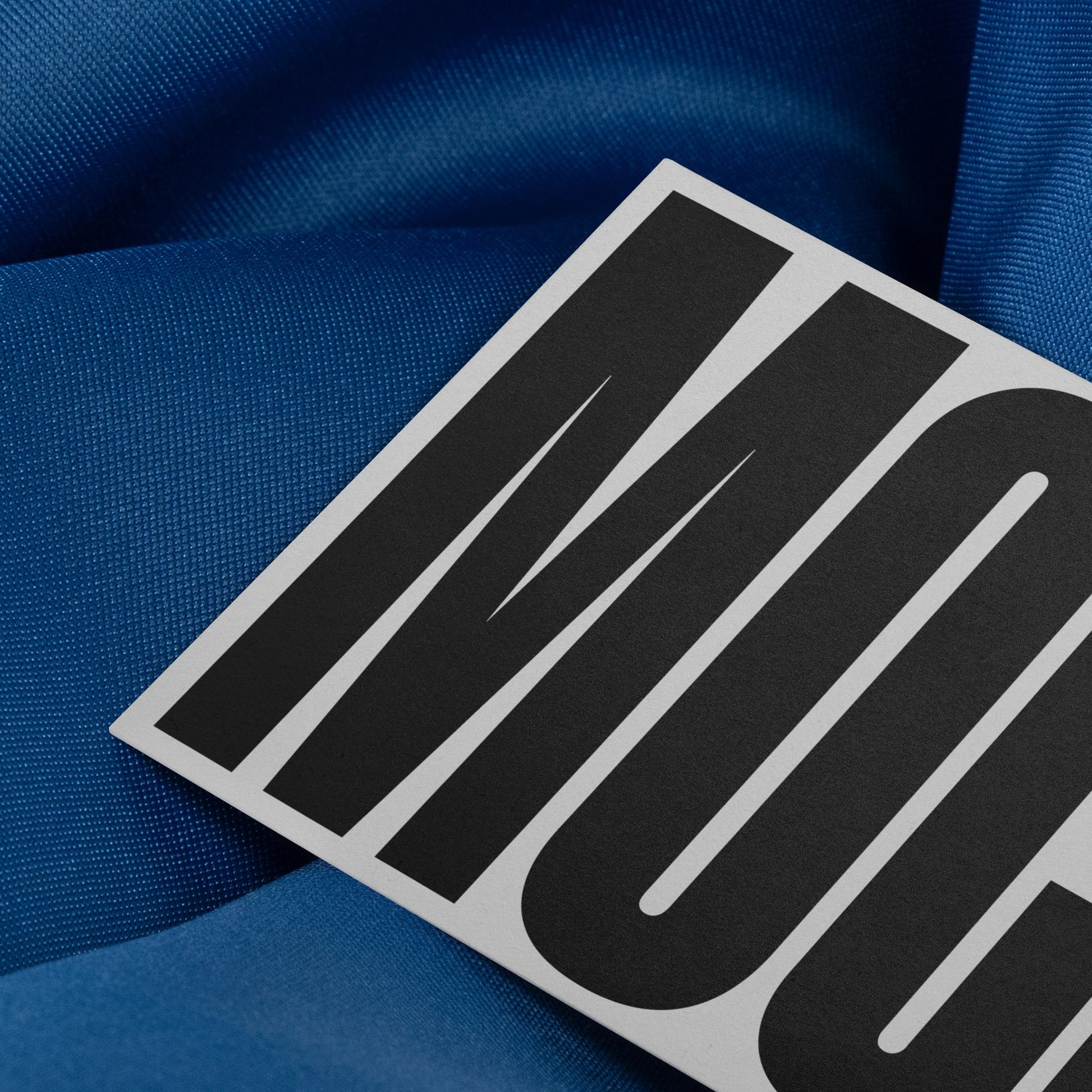 Branding mockup featuring stationery print items, showing a business card design on a blue background made of cloth fabric. Created by Sylvan Hillebrand.