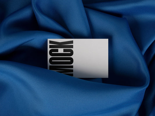 Branding mockup featuring stationery print items, showing a business card design on a blue background made of cloth fabric. Created by Sylvan Hillebrand.