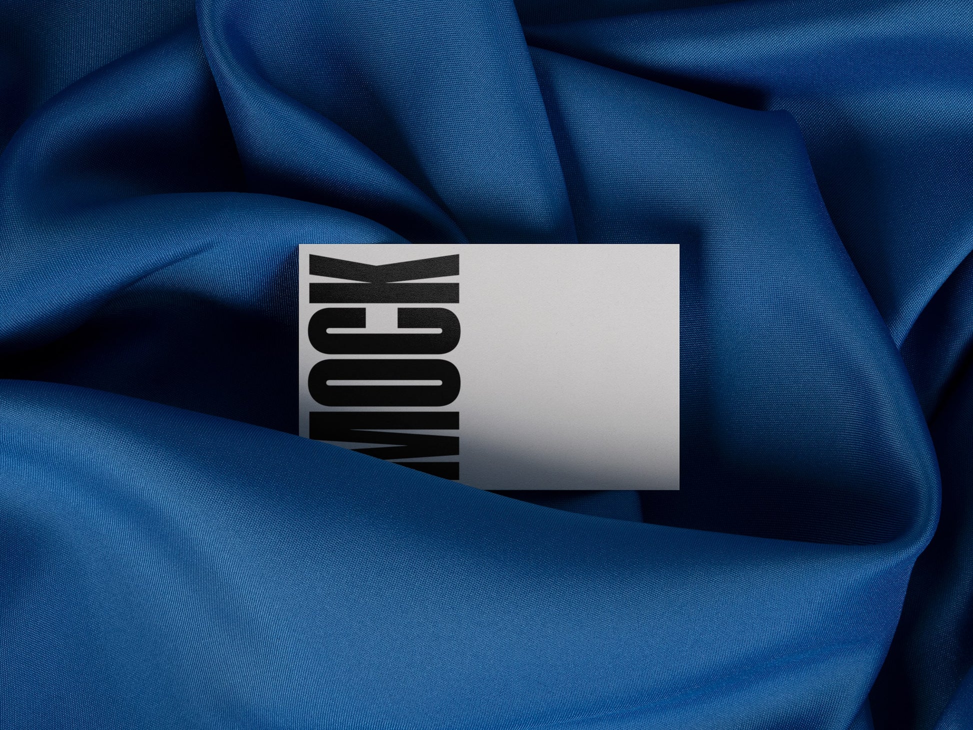 High-quality branding mockup featuring stationery print items, showing a business card on a blue background made of cloth fabric. Created by Sylvan Hillebrand.